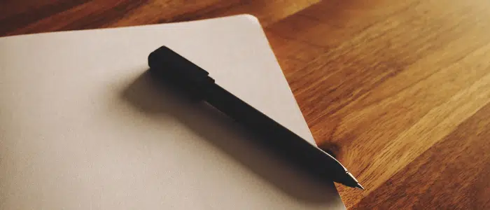 A pen lays on top of a file folder on an office desk